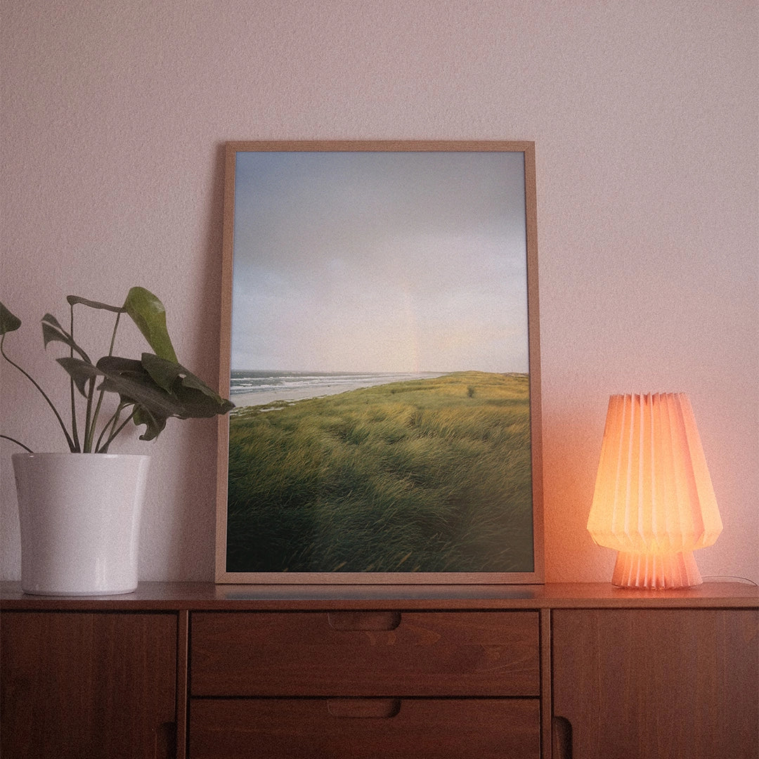 A poster with the photographic motif “Danish Dawn” by POWSTR hanging in a living room.