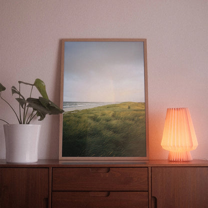 A poster with the photographic motif “Danish Dawn” by POWSTR hanging in a living room.